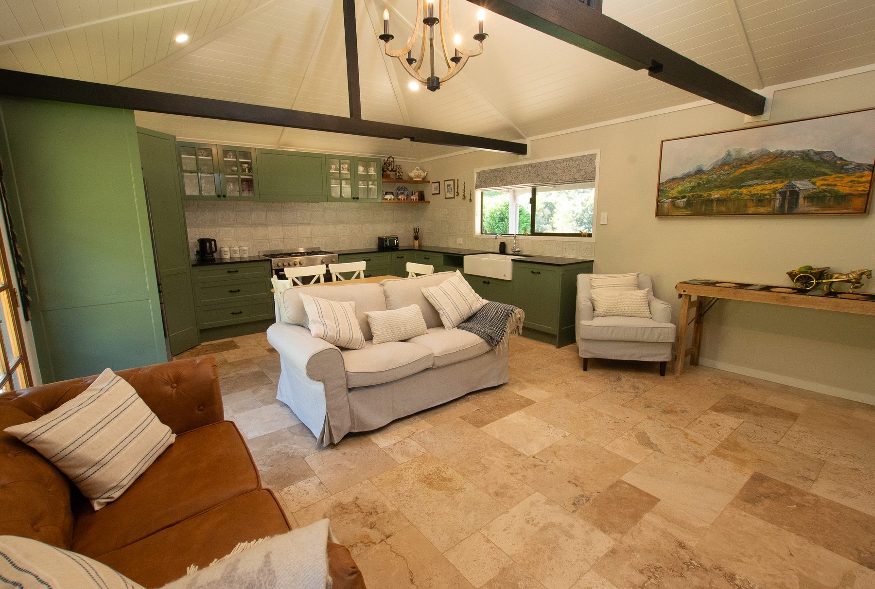 Open-plan living and heritage-green kitchen under a cathedral ceiling